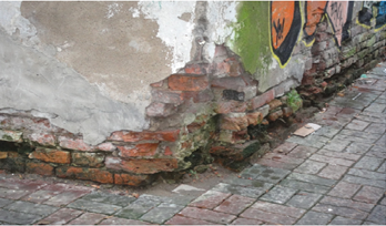 Фото цокольной части стены здания с фрагментами разрушения кирпичной кладки